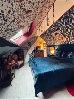White Rabbit House — chambre mansardée avec papier peint floral et lit forgé
