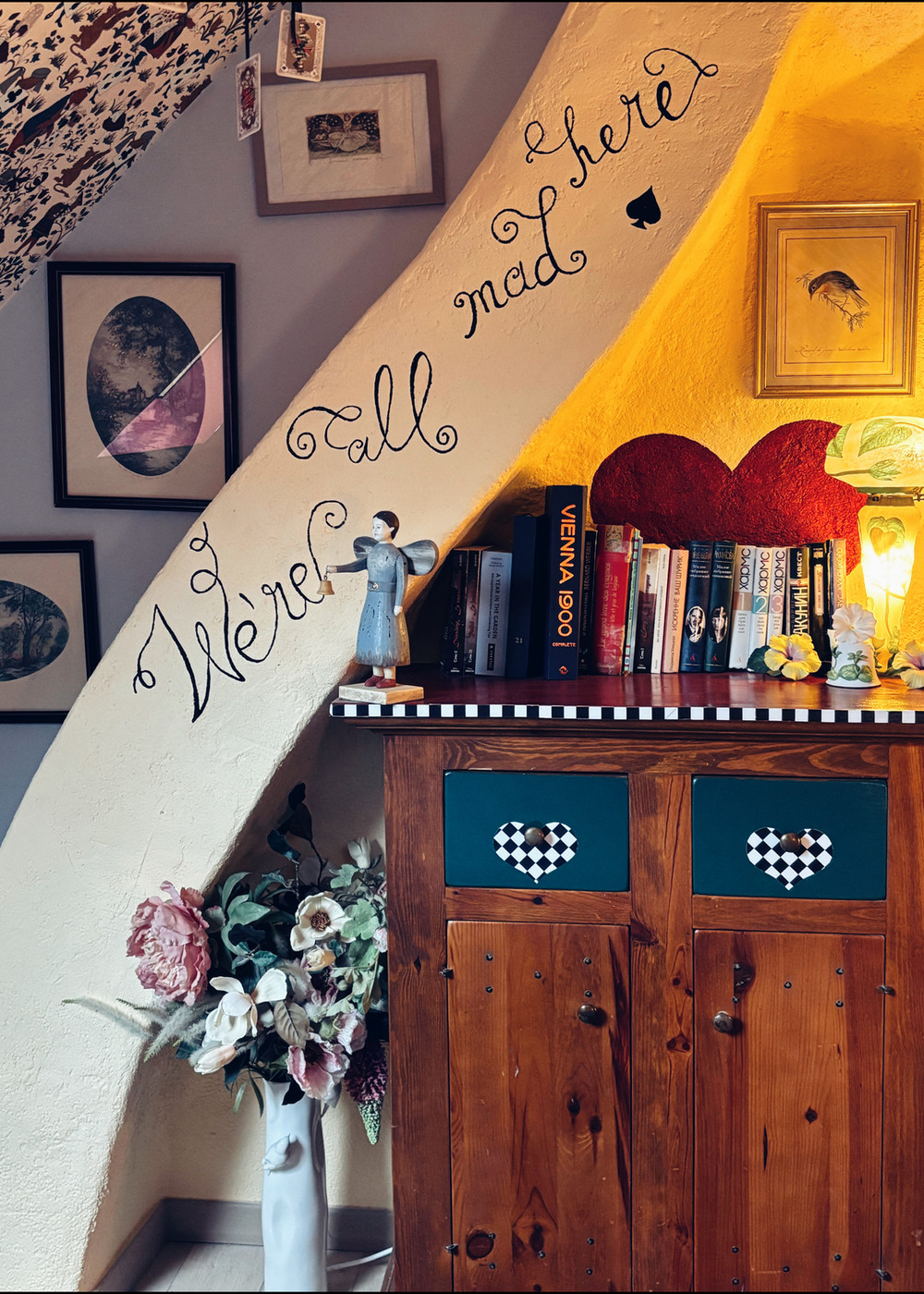 Coin salon avec étagère à coeur rouge, livres anciens et cadres fantaisistes — chambre d'hôte Wonderland21 près de Disneyland Paris